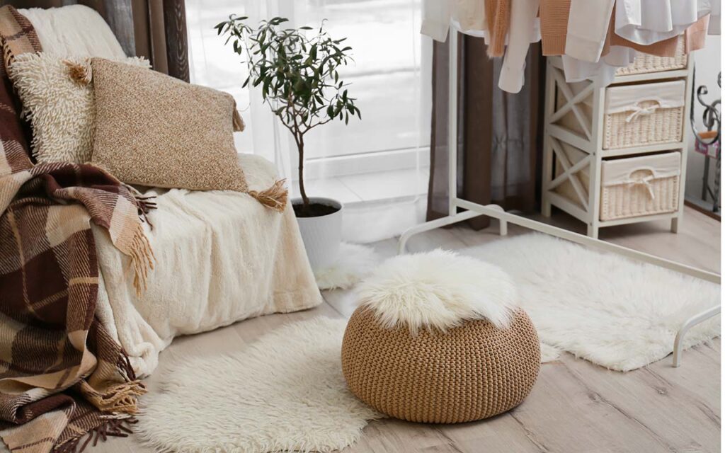Interior of cozy living room with pouf, chair and clothes