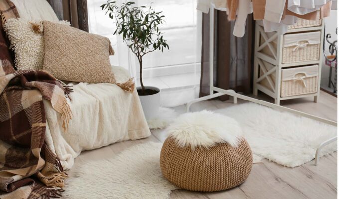 Interior of cozy living room with pouf, chair and clothes